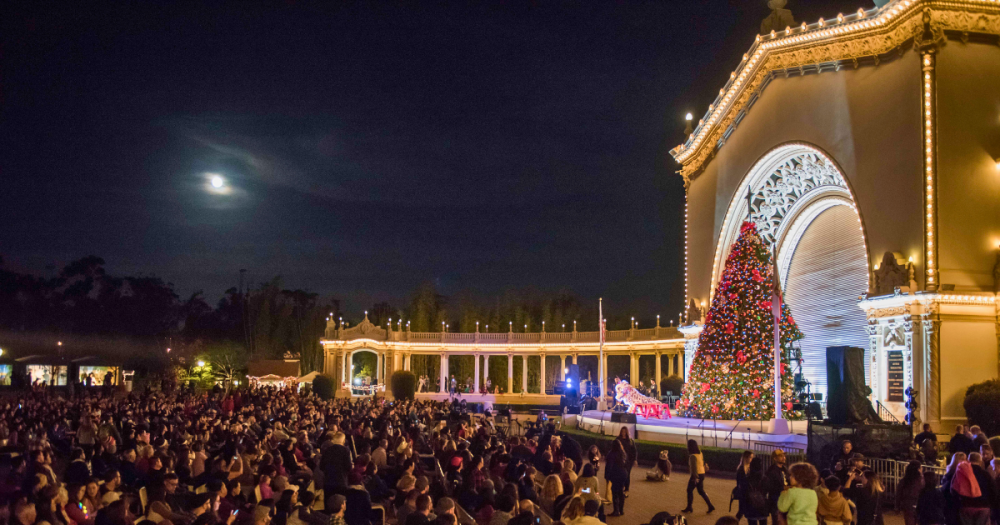 people doing a performance on the stage during december nights event in front of a christmas tree. 