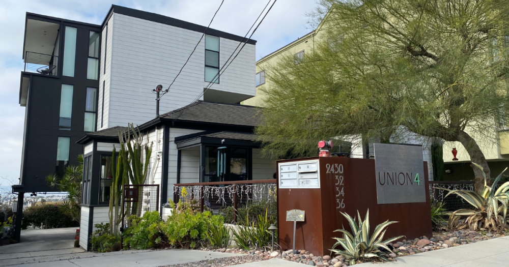 front view of a house with apartments behind it surrounded by landscape