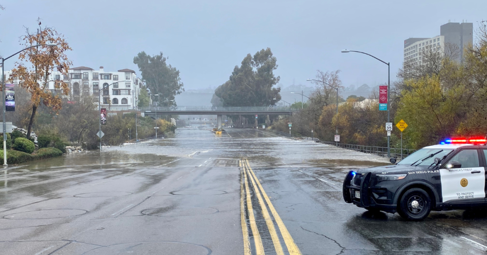 a flooded street being blocked off from a cop car. 