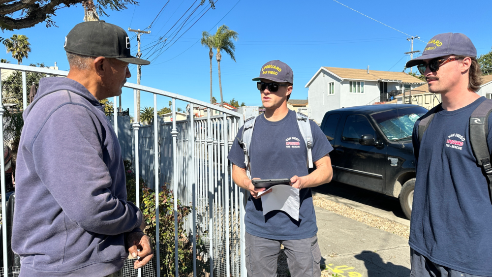 Two lifeguards asking a resident questions in their front drive way 