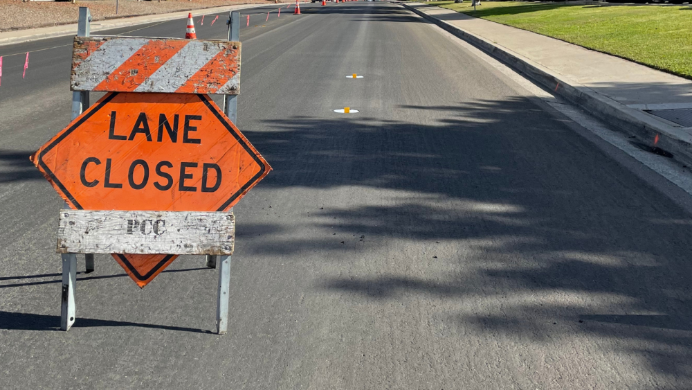 two way road with a sign on the right side of the lane that says lane closed for slurry seal work