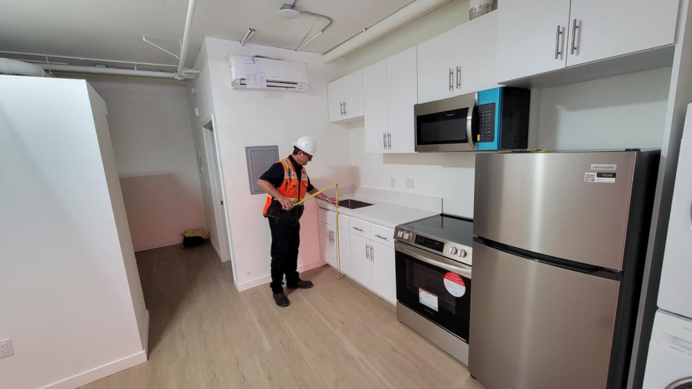 person measuring the height of a counter inside a kitchen.