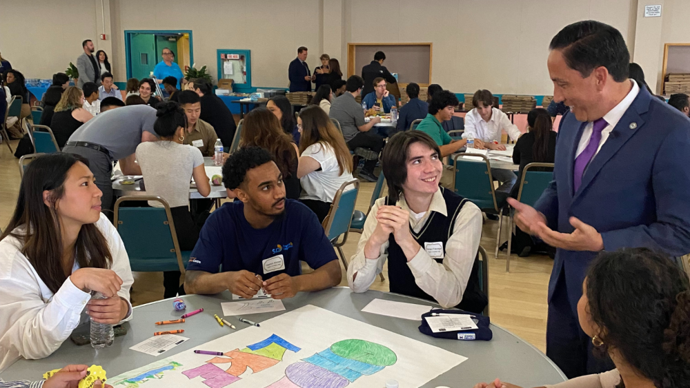 Mayor Gloria speaking with City interns at a table. 