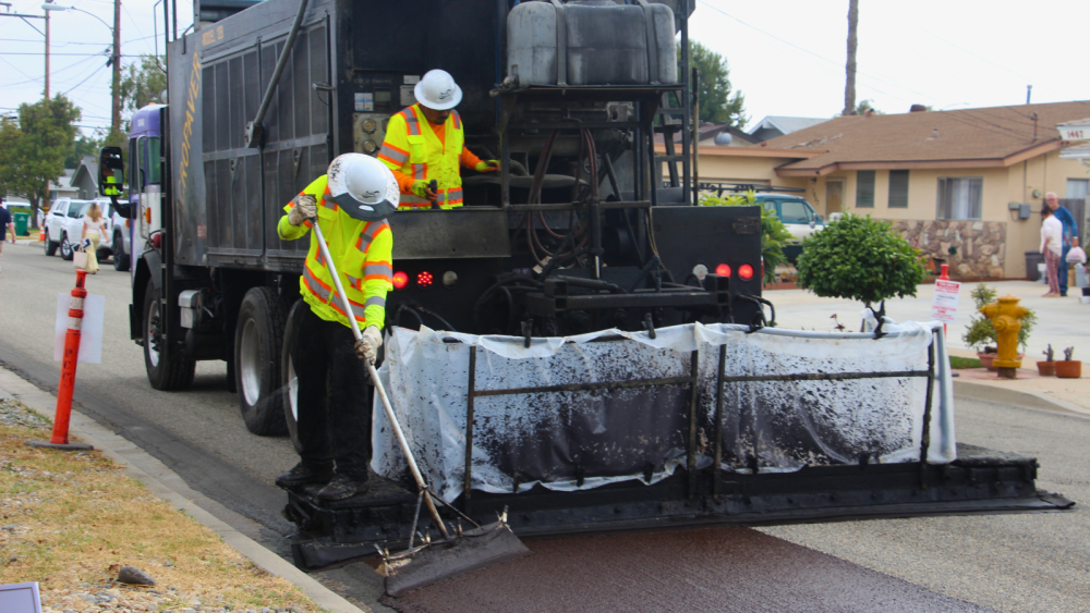 city crews wearing bright yellow vests doing slurry seal work