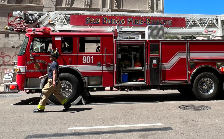 side view of a fire truck with a firefighter walking by