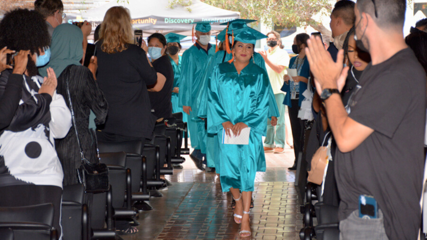 career online high school graduates walking down an aisle&#44; surrounded by cheering people