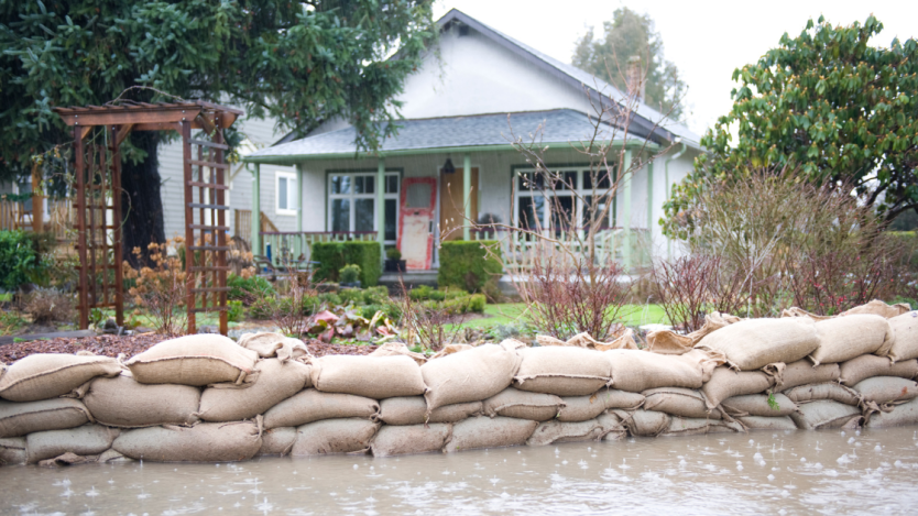 front view of a one-story house with sandbags in front of it to prevent water from flooding the house