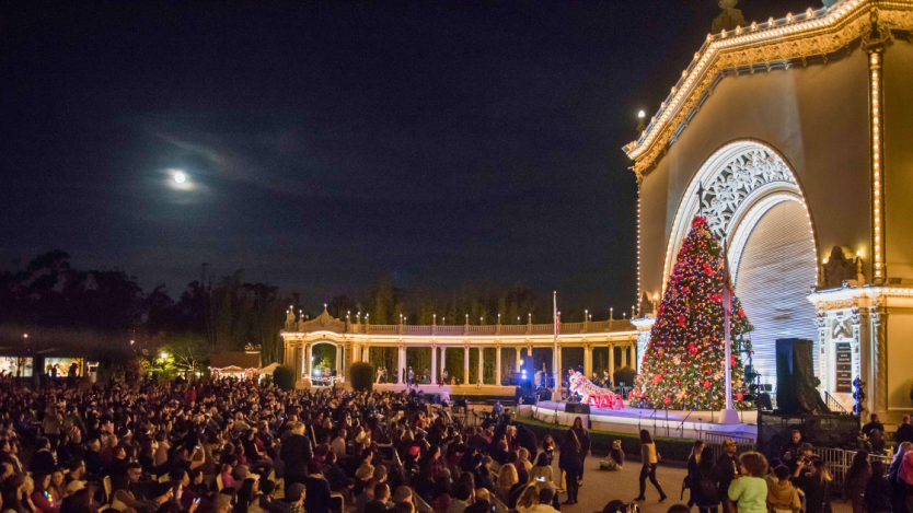 people doing a performance on the stage during december nights event in front of a christmas tree. 