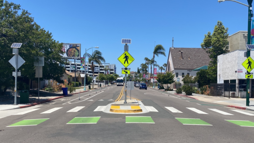 center view of a street with a bike lane and cross walk with safety lights. 