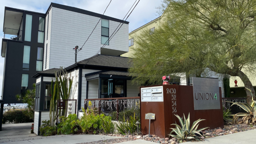 front view of a house with apartments behind it surrounded by landscape