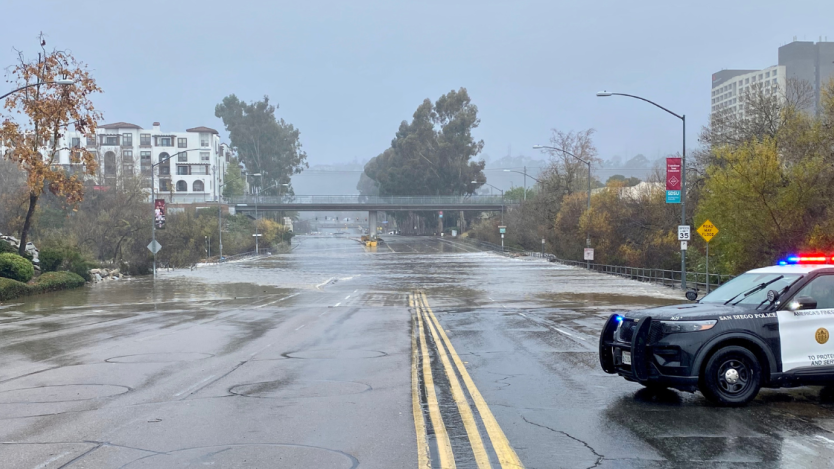 a flooded street being blocked off from a cop car. 