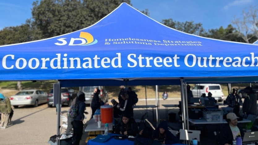 Coordinated Street Outreach City tent in a parking lot with tables set under the tent to help with outreach services.