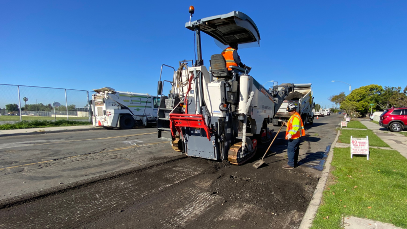 crews working on mill and pave in front of a neighborhood 