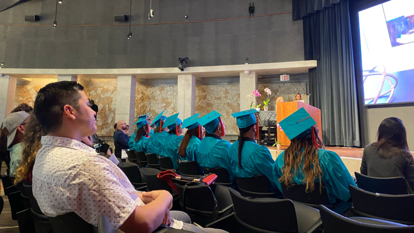 graduates and their families sitting in an auditorium facing the stage. 