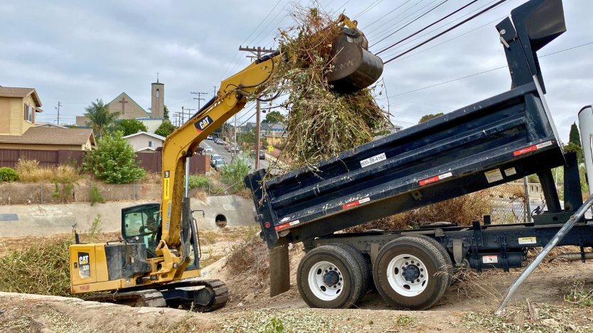 crane removing vegetation from storm channel